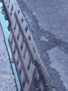 Cette photographie montre principalement une série de **pneus usagés** alignés sur une surface en béton, probablement un trottoir ou une aire de stockage.La **composition** est simple et linéaire, avec un **cadrage serré** mettant en valeur les pneus. La **lumière** semble naturelle, mais diffuse, créant des ombres peu marquées. Les **couleurs dominantes** sont les teintes grises et noires des pneus, contrastant avec le bleu-gris du béton.Le style est **documentaire et réaliste**, sans retouche apparente. L’ambiance est **minérale et industrielle**, évoquant l’abandon ou le recyclage.