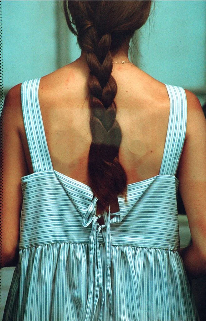 Le dos d'une femme en robe, appuyée contre une vitre