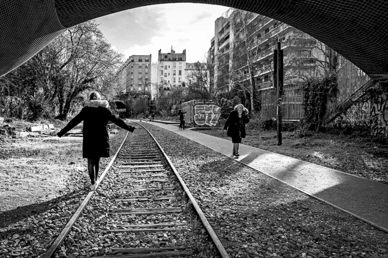 Thierry · 15/02/2020 · 3840 x 2560 Cette photographie en noir et blanc capture un sujet principal : une personne en mouvement sur une voie ferrée, vue de dos. La composition met en valeur une perspective dynamique, avec des rails convergeant vers l’horizon.Le cadrage est serré sur les rails, encadrés par une arche sombre, créant un effet tunnel. La lumière est douce, avec des contrastes marqués entre ombres et clartés, accentuant l’ambiance mélancolique.Les couleurs dominantes sont les nuances de gris, renforçant le côté intemporel et dramatique. Le style est documentaire et artistique, évoquant une atmosphère à la fois solitaire et poétique, presque nostalgique.