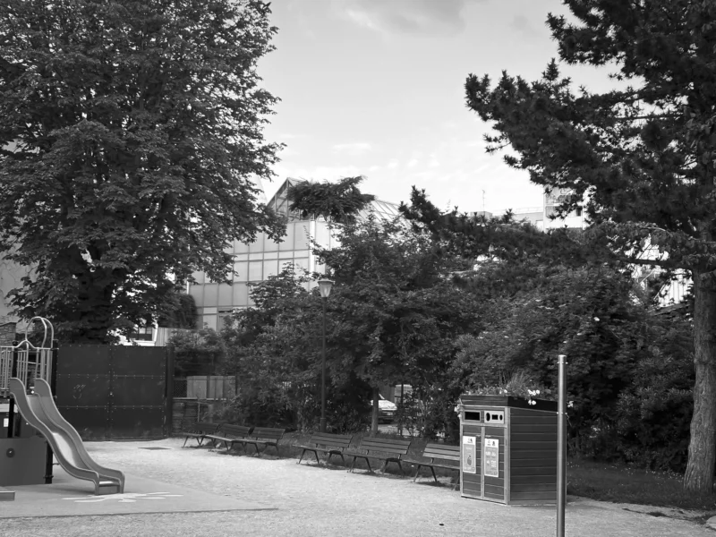 Thierry · 04/07/2025 · 3840 x 2880 Cette photographie en noir et blanc montre un espace extérieur résidentiel. Le sujet principal semble être un parc ou une aire de jeux, avec un toboggan et un bac à sable en arrière-plan.La composition est équilibrée, avec des arbres et des bâtiments en arrière-plan. Le cadrage inclut une partie du ciel et des éléments urbains, créant une ambiance à la fois naturelle et urbaine. La lumière est douce, probablement naturelle, mais légèrement voilée, ce qui adoucit les contrastes.Les tons dominants sont les gris et noirs, typiques du noir et blanc, renforçant une ambiance calme et intemporelle. Le style est documentaire et sobre, évoquant une ambiance paisible et quotidienne.