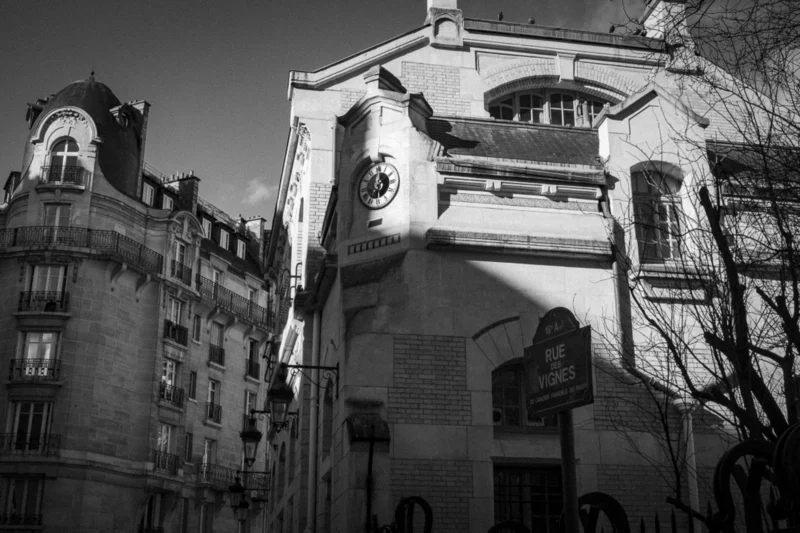 Thierry · 04/07/2025 · 3840 x 2560 Cette photographie en noir et blanc met en scène une façade d’immeuble parisien typique. Le sujet principal est un bâtiment avec des détails architecturaux classiques, comme les balcons en fer forgé et les fenêtres à petits carreaux.La composition est verticale, centrée sur l’édifice avec un cadrage serré. La lumière, naturelle et contrastée, accentue les ombres et les textures. Les couleurs dominantes, bien que monochromes, varient des tons clairs aux noirs profonds.Le style est documentaire et esthétique, évoquant une ambiance historique et urbaine, presque mélancolique.