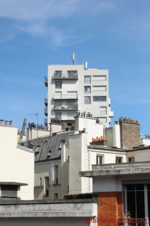 Cédric · 06/09/2025 · 3279 x 4918 Cette photographie montre un ensemble d'immeubles urbains en cours de rénovation ou de construction. Le sujet principal est un bâtiment moderne en gris, partiellement achevé, contrastant avec les structures anciennes en brique et pierre autour.La composition est verticale, mettant en valeur la hauteur des bâtiments. Le cadrage est serré, centré sur ces structures. La lumière est naturelle, claire et ensoleillée, créant des ombres nettes. Les couleurs dominantes sont les tons gris, beige et brun, avec des touches de bleu dans le ciel.Le style est documentaire, reflétant une ambiance urbaine en transformation, entre modernité et héritage architectural.