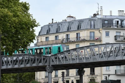 Jean-Marc · 13/09/2025 · 3840 x 2560 Cette photographie montre un tramway vert circulant sur un pont métallique. Le sujet principal est le tram, encadré par des bâtiments parisiens typiques aux façades claires et aux toits gris.La composition met en valeur le contraste entre l’architecture classique et la modernité du tramway. Le cadrage est serré sur le pont, avec une perspective légèrement basse.La lumière est naturelle et douce, suggérant un jour nuageux. Les couleurs dominantes sont les tons gris-beige des bâtiments, le vert du tram et le bleu-gris du ciel. L’ambiance est urbaine et dynamique, mêlant tradition et modernité.