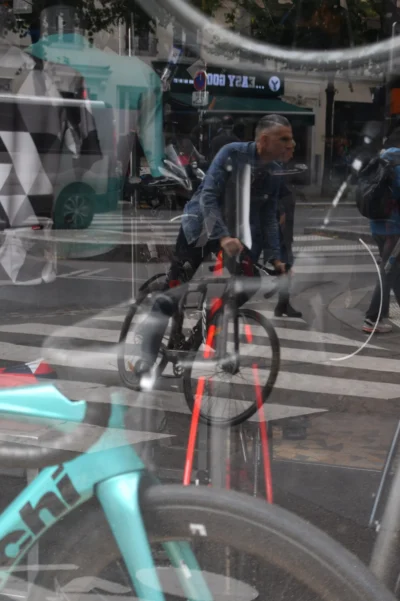 Vincent · 13/09/2025 · 2557 x 3840 Cette photographie montre un cycliste comme sujet principal, reflété dans une surface vitrée. La composition joue sur la symétrie et le reflet, créant une impression de mouvement et de duplication.Le cadrage est serré sur le vélo et le cycliste, avec des éléments urbains en arrière-plan. La lumière est naturelle, légèrement tamisée, avec des ombres douces. Les couleurs dominantes sont les teintes froides (bleu turquoise du vélo, gris de la ville) et quelques touches chaudes (rouge du cadre).Le style est réaliste et urbain, évoquant une ambiance dynamique et moderne dans un cadre citadin.