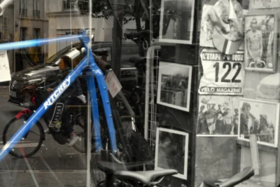 Vincent · 13/09/2025 · 3840 x 2565 Cette photographie montre principalement un vélo bleu garé devant une vitrine. La composition inclut aussi des affiches anciennes en noir et blanc, dont une avec le numéro "122". Le cadrage est serré, mettant en valeur le vélo et les affiches en arrière-plan.La lumière semble naturelle, avec des contrastes doux. Les couleurs dominantes sont les tons bleus du vélo et les noirs et blancs des affiches. Le style est urbain et rétro, évoquant une ambiance mélancolique et nostalgique, mêlant modernité et passé.