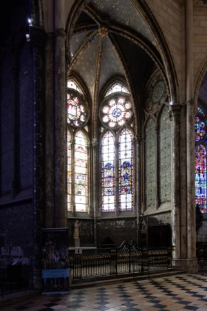 Claude · 3611 x 5417 Cette photographie représente l'intérieur d'une cathédrale gothique. Le sujet principal est un ensemble de vitraux colorés et lumineux, encadrés par des arcs ogivaux élancés. La composition met en valeur la hauteur des fenêtres et la structure architecturale imposante.Le cadrage est serré sur les vitraux, avec une perspective verticale accentuant la verticalité des piliers. La lumière naturelle filtre à travers les vitraux, créant des jeux d'ombres et de clarté. Les couleurs dominantes sont les bleus, rouges et verts des vitraux, sur un fond de pierre grise.L'ambiance est solennelle et sacrée, typique du style gothique.