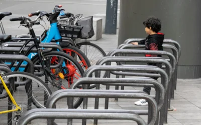 Muriel · 13/09/2025 · 2048 x 1280 Cette photographie montre un enfant assis sur un banc métallique, observant des vélos rangés dans des supports. Le sujet principal est l’enfant, en arrière-plan flou.La composition oppose les vélos colorés et organisés à la posture contemplative de l’enfant. Le cadrage est serré sur le banc et l’enfant, avec une profondeur de champ réduite.Les couleurs dominantes sont vives (bleu, rouge des vélos) contrastant avec les tons gris du béton et du métal. La lumière semble naturelle, créant des ombres douces. L’ambiance est calme et urbaine, mêlant mouvement et immobilité.