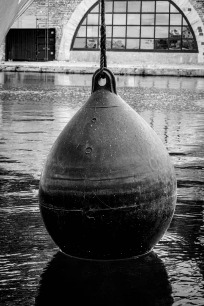 Pascal N. · 13/09/2025 · 1440 x 2160 Cette photographie met en scène un **boulet de canon** comme sujet principal, posé sur l’eau. La **composition** est épurée, centrée sur l’objet avec un arrière-plan flou.Le **cadrage** est serré, mettant en valeur les détails du boulet et son reflet dans l’eau. La **lumière**, douce et diffuse, crée des contrastes subtils. En **noir et blanc**, les tons varient du clair au foncé, accentuant les textures.L’ambiance est **nostalgique et historique**, renforcée par le style sobre et le flou de l’arrière-plan architectural.