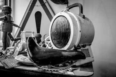 Pascal N. · 13/09/2025 · 3240 x 2160 Cette photographie en noir et blanc met en scène une vieille machine industrielle, probablement un appareil de soudure ou de chauffage, comme sujet principal. La composition montre des éléments mécaniques et des outils anciens, évoquant un atelier ou un espace de travail désuet.Le cadrage est serré sur la machine, avec des détails techniques en premier plan, et un fond légèrement flou. La lumière est douce et contrastée, créant des ombres marquées qui accentuent le côté vintage. Les couleurs dominantes, bien que monochromes, jouent sur les nuances de gris et de noir, renforçant l’ambiance nostalgique et industrielle. Le style rappelle le réalisme documentaire, évoquant une époque révolue.
