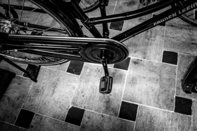 Pascal N. · 13/09/2025 · 3240 x 2160 Cette photographie met en scène un vélo fixé à un support mural. Le sujet principal est le cadenas accroché à la roue arrière, soulignant la sécurité.La composition est épurée, avec un cadrage serré sur le cadenas et une partie des roues. L'angle de vue est légèrement en contre-plongée, offrant une perspective dynamique.En noir et blanc, l'image joue sur les contrastes lumineux, accentuant les textures et ombres. Les couleurs dominantes, bien que grises, varient entre tons clairs et foncés, renforçant l'ambiance urbaine et minimaliste. Le style est documentaire et intemporel, évoquant une atmosphère à la fois banale et poétique.
