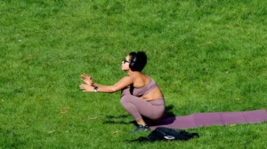 Pascale · 06/09/2025 · 700 x 393 Cette photographie montre une personne en train de faire des exercices au sol sur une pelouse. Le sujet principal est une femme en position de gainage ou d’étirement, vêtue d’un haut sportif.La composition est simple et centrée, avec un cadrage serré. La lumière naturelle, probablement ensoleillée, éclaire la scène, créant des ombres douces. Les couleurs dominantes sont les verts vifs de l’herbe et les tons neutres du vêtement de la personne.Le style est réaliste et dynamique, évoquant une ambiance active et saine, typique d’une séance de sport en extérieur.