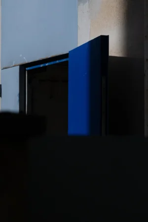 Jean-Paul · 06/09/2025 · 2000 x 3000 Cette photographie met en scène un **livre bleu** posé verticalement près d’une **porte entrouverte**. La **composition** est épurée, centrée sur le livre, avec un cadrage serré.La **lumière** naturelle, tamisée, crée des contrastes doux entre ombres et clarté, accentuant le bleu profond du livre. Les **couleurs dominantes** sont le bleu intense et les tons neutres (gris, blanc).Le style est **minimaliste et contemplatif**, évoquant une ambiance **calme et introspective**, presque mélancolique. L’espace semble vide, renforçant la solitude du livre.