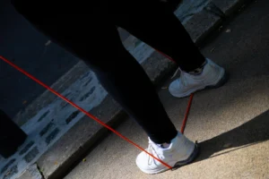 Jean-Paul · 06/09/2025 · 3000 x 2000 Cette photographie met en scène des **pieds chaussés de baskets blanches** avec des lacets rouges, posés sur un sol en béton. Le **sujet principal** est les chaussures, isolées par un cadrage serré.La **composition** est épurée, avec des lignes rouges ajoutées pour guider le regard. La **lumière** naturelle crée des ombres marquées, accentuant le contraste. Les **couleurs dominantes** sont le gris du béton, le blanc des baskets et le rouge des lacets, apportant une touche dynamique.Le style est **minimaliste et urbain**, évoquant une ambiance **moderne et contemporaine**, presque abstraite.