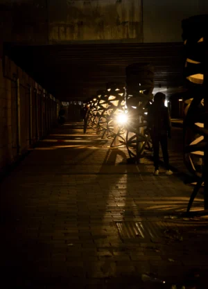 Claude · 3777 x 5256 Cette photographie capture un couloir urbain nocturne et étroit, éclairé par des lampadaires. Le sujet principal semble être l'alignement des vélos stationnés et la lumière tamisée qui guide le regard vers l'arrière-plan.La composition est symétrique, avec des vélos alignés de chaque côté. Le cadrage est serré, créant une sensation de profondeur et de perspective. La lumière douce et jaunâtre, typique des éclairages publics, domine, tandis que les couleurs sont sombres et contrastées, renforçant une ambiance nocturne et mystérieuse. Le style est réaliste et sobre, évoquant une atmosphère calme et presque mélancolique.