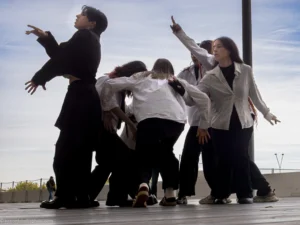 Benoit · 18/10/2025 · 4050 x 3038 Cette photographie capture un groupe de personnes en mouvement, probablement en train de danser ou de faire une activité chorégraphique. Le sujet principal est l'ensemble des individus, dont les postures dynamiques et étirées dominent la composition.Le cadrage est serré, mettant en valeur les corps en action. La lumière naturelle, douce et légèrement diffuse, crée des ombres douces et un contraste modéré. Les couleurs dominantes sont des tons neutres : gris, noir et blanc, avec des vêtements sombres et clairs.L’ambiance est énergique et expressive, évoquant un style contemporain et spontané.
