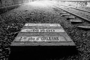 Philippe · 04/10/2025 · 3000 x 2001 Cette photographie en noir et blanc montre une plaque gravée au sol près de rails de chemin de fer. Le sujet principal est la plaque indiquant "Strasbourg, 122 km, pte d’Orléans".La composition est simple et épurée, avec un cadrage serré sur la plaque et les rails en arrière-plan. La lumière est douce, créant des contrastes nets entre ombres et lumières. Les couleurs dominantes sont les nuances de gris, typiques du noir et blanc.Le style est documentaire et sobre, évoquant une ambiance historique et mélancolique, presque nostalgique.