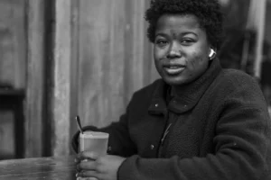 Don · 11/10/2025 · 5976 x 3984 Cette photographie en noir et blanc met en scène une femme comme sujet principal, assise à une table. Son expression est sérieuse et pensif.La composition est simple, avec un cadrage serré sur son visage et ses épaules. La lumière est douce et naturelle, éclairant principalement son visage et créant des contrastes subtils.L’absence de couleurs accentue les textures et les jeux d’ombres. Le style est réaliste et documentaire, évoquant une ambiance intime et contemplative, presque mélancolique.