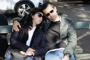 Cédric · 11/10/2025 · 4803 x 3202 Cette photographie montre un couple assis sur un banc, en position intime et complice. Le sujet principal est leur relation et leur proximité.La composition est simple et centrée, avec un cadrage serré sur les deux personnes. L'arrière-plan est flou, mettant l'accent sur eux. La lumière semble naturelle, probablement en extérieur par temps couvert ou en début de soirée. Les couleurs dominantes sont les tons neutres (gris, noir) et quelques touches de bleu et blanc.Le style est réaliste et spontané, évoquant une ambiance chaleureuse et intime.