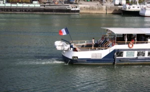 Laurence · 6960 x 4271 Cette photographie montre un bateau de croisière fluviale comme sujet principal. La composition met en valeur le navire en mouvement sur l’eau, avec un drapeau français flottant à l’arrière. Le cadrage est serré, capturant une partie du bateau et de l’eau environnante.La lumière semble naturelle, probablement en journée, avec des reflets sur l’eau. Les couleurs dominantes sont les bleus (eau, ciel) et les tons blancs et gris du bateau. Le style est documentaire et réaliste, évoquant une ambiance paisible et touristique.