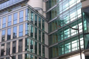 Laurence · 6960 x 4640 Cette photographie met en scène un immeuble moderne en angle de vue. Le sujet principal est la façade en verre et métal, avec des fenêtres rectangulaires et des balcons en saillie. La composition joue sur les lignes verticales et horizontales, créant un effet dynamique.Le cadrage est serré, mettant en valeur les détails architecturaux. La lumière naturelle, probablement en journée, éclaire uniformément la structure, accentuant les reflets sur les vitres. Les couleurs dominantes sont les tons gris, verts et blancs, typiques d’un style contemporain et urbain. L’ambiance est à la fois froide et sophistiquée, reflétant une architecture fonctionnelle et moderne.