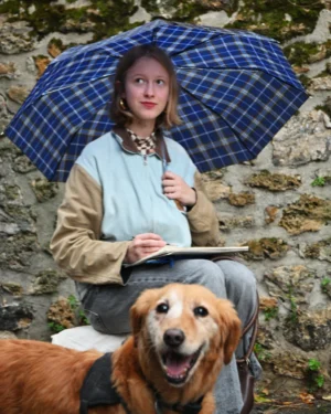 Mary · 15/11/2025 · 2227 x 2784 Cette photographie met en scène une jeune femme comme sujet principal, assise sous un parapluie à carreaux bleus et blancs. Elle tient un carnet, avec un chien golden retriever souriant devant elle.La composition est équilibrée, avec un cadrage serré sur les deux sujets. La lumière semble naturelle, douce et légèrement tamisée, créant une ambiance paisible. Les couleurs dominantes sont les tons pastel (bleu, beige) et les teintes chaudes du chien. Le style est naturel et spontané, évoquant une scène intimiste et apaisante dans un cadre extérieur, probablement en forêt ou en montagne.