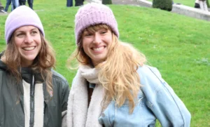 Laurence · 6960 x 4193 Cette photographie met en scène deux femmes souriantes comme sujets principaux. Elles sont cadrées en plan serré, posant côte à côte sur un fond de pelouse verte.La lumière semble naturelle et douce, probablement en extérieur par temps clair. Les couleurs dominantes sont les tons froids (bleu du manteau, gris du pull) et chauds (beige et rose des accessoires). L’ambiance est conviviale et détendue, évoquant une journée agréable en plein air. Le style est simple et spontané, avec une touche de décontraction.