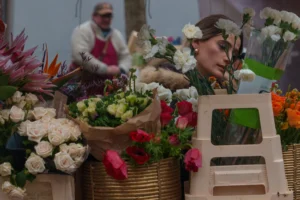 Don · 3003 x 2002 Cette photographie met en scène un marché floral. Le sujet principal est une personne partiellement visible, entourée de bouquets variés et colorés. La composition montre des fleurs fraîches disposées dans des paniers et des vases, avec une attention particulière aux détails des pétales.Le cadrage est serré sur les fleurs avant-plan, créant une profondeur de champ qui floute légèrement l'arrière-plan. La lumière semble naturelle, douce et diffuse, mettant en valeur les teintes vives. Les couleurs dominantes sont les blancs, roses, verts et touches de rouge et violet.L’ambiance est chaleureuse et artisanale, évoquant un marché traditionnel et vivifiant.