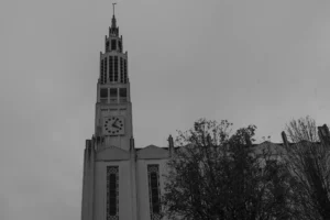 Don · 6351 x 4234 Cette photographie met en scène une **cloche d’église** ou un **beffroi** comme sujet principal. La composition est simple et épurée, avec un cadrage serré sur la structure, laissant peu de place aux éléments environnants.La lumière est douce mais diffuse, typique d’un jour nuageux, créant des contrastes atténués. Les **couleurs dominantes** sont en noir et blanc, ce qui accentue les textures et les formes sans distraction chromatique.Le style est **minimaliste et classique**, évoquant une ambiance **nostalgique et intemporelle**, renforcée par le flou des arbres en arrière-plan.
