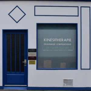 Deniz · 22/11/2025 · 2127 x 2127 Cette photographie montre la façade d’un cabinet de **kinésithérapie**, avec pour sujet principal une porte bleue et une vitrine centrale. La composition est symétrique, avec des lignes géométriques nettes (carrés, losange). Le cadrage est serré, mettant en valeur les éléments architecturaux.La lumière semble naturelle et douce, éclairant uniformément la scène. Les couleurs dominantes sont le **bleu** (porte, encadrements) et le **gris clair** (murs), avec des touches de blanc. Le style est épuré et professionnel, évoquant une ambiance **calme et thérapeutique**, typique d’un cabinet médical.