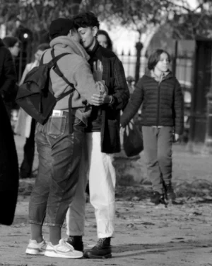 Thomas · 01/11/2025 · 1080 x 1350 Cette photographie en noir et blanc met en scène un couple comme sujet principal, en train de s'embrasser. La composition est dynamique, avec des personnes en arrière-plan légèrement floues, créant une sensation de profondeur.Le cadrage est serré sur le couple, mais inclut aussi des éléments contextuels comme les passants et un environnement urbain. La lumière est douce, naturelle, et semble provenir d’une source diffuse, adoucissant les contours.L’absence de couleurs renforce l’émotion et la simplicité de la scène, évoquant une ambiance intime et nostalgique dans un cadre urbain animé. Le style est documentaire et spontané.