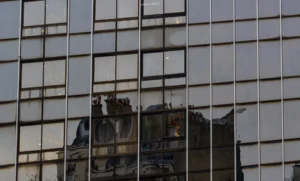 Laurent · 3589 x 2160 Cette photographie montre une **reflection dans une façade vitrée**, probablement d’un immeuble de bureaux. Le **sujet principal** est la silhouette floue d’un autre bâtiment, partiellement reflétée.La **composition** repose sur une **symétrie** et une répétition des motifs géométriques des vitres. Le **cadrage** est serré, centré sur les reflets. La **lumière**, douce et tamisée, crée des contrastes subtils. Les **couleurs dominantes** sont des teintes grises et bleutées, avec des nuances froides.Le style est **minimaliste et urbain**, évoquant une **ambiance moderne et neutre**, presque mélancolique.