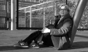 Pascale · 06/12/2025 · 1250 x 741 Cette photographie en noir et blanc met en scène un homme comme sujet principal, assis sur un banc avec une posture détendue. La composition est simple et épurée, avec un cadrage serré sur le sujet, isolé devant une clôture métallique.La lumière semble naturelle, douce et légèrement contrastée, créant des ombres subtiles. Les couleurs dominantes sont les nuances de gris, typiques du noir et blanc, renforçant une ambiance introspective et mélancolique. Le style est réaliste et documentaire, évoquant une atmosphère calme et contemplative.