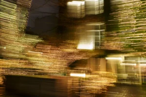 Thierry · 20/12/2025 · 3840 x 2560 Cette photographie capture un mouvement flou, probablement dû à une longue exposition ou à un déplacement rapide de l'appareil. Le sujet principal semble être une structure architecturale, comme un pont ou une passerelle, avec des éléments métalliques et des lumières artificielles.La composition est dynamique, avec des lignes courbes et des jeux de transparence. Le cadrage est serré, mettant l'accent sur les détails et les textures. Les couleurs dominantes sont des tons chauds et dorés, avec des reflets verts et des éclats lumineux jaunes.Le style est abstrait et artistique, évoquant une ambiance onirique et presque hypnotique.