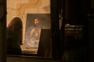 Ahmet · 20/12/2025 · 2500 x 1665 Cette photographie met en scène un portrait peint, probablement une réplique de la Joconde, placé devant une fenêtre. Le sujet principal est ce tableau, éclairé par une lumière douce et tamisée.La composition est simple, avec un cadrage serré qui isole le portrait. La lumière, naturelle et filtrée, crée une ambiance chaleureuse et mystérieuse. Les couleurs dominantes sont des tons neutres et chauds, avec des reflets dorés.Le style évoque une touche artistique classique, renforcée par le flou et la pénombre environnante, donnant une impression intime et contemplative.