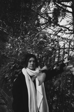 Deniz · 06/12/2025 · 4000 x 6000 Cette photographie en noir et blanc met en scène une personne comme sujet principal, partiellement cachée derrière des branches d'arbres. Le cadrage est serré, centré sur elle, avec un arrière-plan naturel et légèrement flou.La lumière semble douce et naturelle, créant des contrastes subtils. Les couleurs dominantes sont les nuances de gris, renforçant une ambiance introspective et mélancolique. Le style est sobre et artistique, évoquant une atmosphère poétique et contemplative, presque cinématographique.
