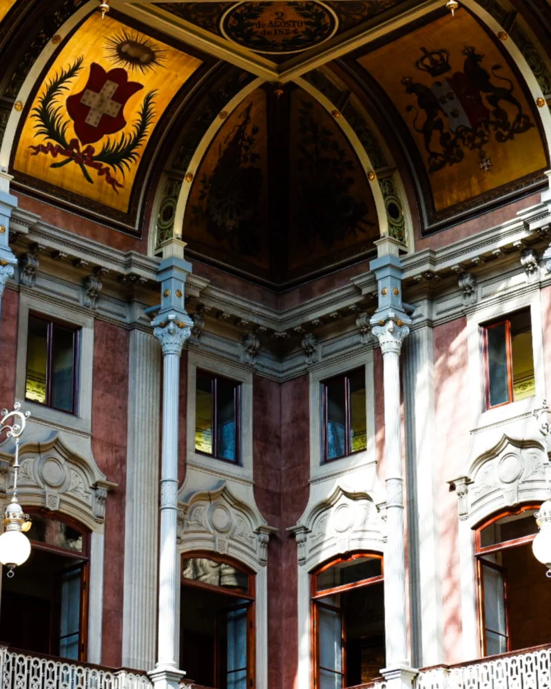 Romain · 2160 x 2700 Cette photographie montre un intérieur architectural somptueux, probablement un théâtre ou un opéra. Le sujet principal est la riche décoration du plafond et des colonnes, ornées de dorures et de fresques.La composition met en valeur les arcs et les balcons élégamment sculptés. Le cadrage est serré, centré sur les détails architecturaux. La lumière, tamisée, accentue les contrastes entre ombres et éclats dorés. Les couleurs dominantes sont les tons chauds (or, rouge, marron) et les touches de blanc.Le style est baroque ou néoclassique, créant une ambiance majestueuse et théâtrale.