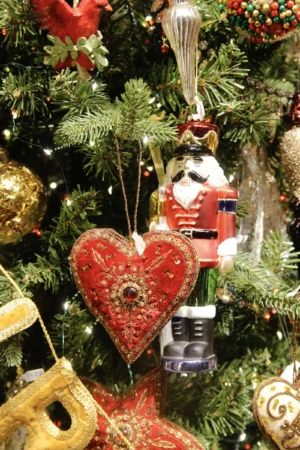 Cédric · 20/12/2025 · 3456 x 5184 Cette photographie montre un sapin de Noël décoré. Le **sujet principal** est une **décoration en forme de cœur rouge** avec des motifs dorés, entourée d’autres ornements festifs.La **composition** est serrée, mettant en valeur les détails des décorations. Le **cadrage** est rapproché, centré sur les éléments colorés. La **lumière** est douce et naturelle, éclairant les objets avec une touche chaleureuse.Les **couleurs dominantes** sont le **rouge, l’or, le vert** et quelques touches de blanc. Le **style** est traditionnel et festif, évoquant une ambiance **chaleureuse et joyeuse**, typique des décorations de Noël.
