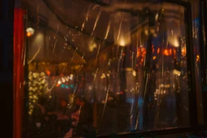Don · 5027 x 3351 Cette photographie capture une scène floue à travers une vitre striée, probablement celle d'un véhicule. Le sujet principal semble être une rue nocturne animée, avec des lumières colorées et des silhouettes floues.La composition est dynamique, avec des lignes verticales des stries de la vitre qui structurent l'image. Le cadrage est serré, centré sur la vitre et son reflet.Les couleurs dominantes sont des teintes chaudes (jaunes, oranges) et des éclats de rouge et bleu, créant une ambiance nocturne et vibrante. Le style est réaliste et légèrement abstrait en raison du flou. L'ambiance est urbaine et mystérieuse, évoquant une nuit animée et mouvementée.
