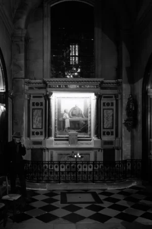 Philippe · 2001 x 3000 Cette photographie en noir et blanc met en scène un **autel ou une chapelle** comme sujet principal. La composition est symétrique, centrée sur un espace sacré éclairé, probablement un retable ou une niche abritant une statue ou une icône religieuse.Le cadrage est serré, mettant en valeur les détails architecturaux et les motifs géométriques du sol. La lumière, douce et contrastée, crée une ambiance solennelle et mystique. Les tons dominants, en niveaux de gris, accentuent la profondeur et la sérénité.Le style est classique et intemporel, évoquant une atmosphère contemplative et sacrée.