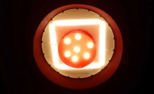 Franck T. · 20/12/2025 · 1400 x 852 Cette photographie montre un **LED rouge** comme sujet principal. Le cadrage est serré, mettant en valeur la lumière émise par les sept petits points lumineux au centre.La composition est simple et centrée, avec un cercle rouge entourant le composant. Les couleurs dominantes sont le **rouge vif** et le **blanc** des LED. La lumière est intense et artificielle, créant une ambiance technique et moderne. Le style est épuré, presque abstrait, évoquant une atmosphère industrielle et futuriste.