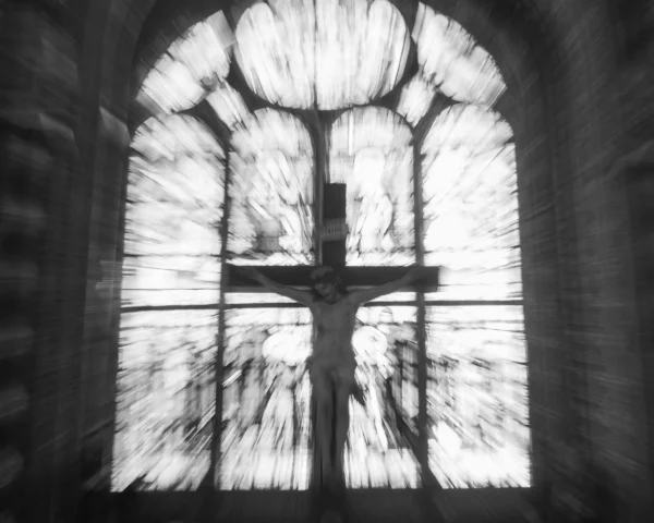 Loubna · 2048 x 1638 Cette photographie met en scène un vitrail représentant une croix, sujet principal. La composition est épurée, centrée sur l'élément religieux. Le cadrage serré isole la fenêtre gothique, accentuant son architecture.La lumière, filtrée et diffuse, traverse les vitraux, créant des jeux de transparence et d'ombres. Les couleurs dominantes sont les tons gris et blancs, typiques d'une photo en noir et blanc, renforçant une atmosphère mystique et contemplative. Le style est sobre et minimaliste, évoquant une ambiance sacrée et introspective.