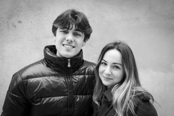 Claude · 5361 x 3574 Cette photographie en noir et blanc met en scène deux jeunes posant côte à côte. Le sujet principal est ce couple souriant, avec une composition symétrique et harmonieuse.Le cadrage est serré, centré sur leurs visages et épaules. La lumière douce et naturelle adoucit les traits, créant des contrastes subtils. L’ambiance est chaleureuse et intime, renforcée par leur proximité et leurs expressions détendues. Le style épuré et sobre, typique du noir et blanc, accentue l’émotion et la simplicité de la scène.
