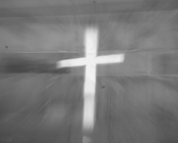 Loubna · 2048 x 1638 Cette photographie met en scène une lumière projetant une silhouette de croix sur une surface texturée, probablement un tissu ou un mur.Le cadrage est serré, centré sur la croix lumineuse. La composition est épurée et minimaliste, avec une ambiance sobre et contemplative. Les couleurs dominantes sont les tons gris et blancs, renforçant un style monochrome et presque abstrait. La lumière, douce et diffuse, crée une atmosphère mystique et apaisante, évoquant une dimension spirituelle ou sacrée.
