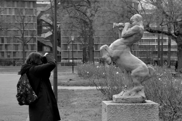 Vincent · 17/01/2026 · 4434 x 2957 Cette photographie en noir et blanc met en scène une personne prenant une photo d'une statue équestre. Le sujet principal est cette statue dynamique, représentant un cavalier en mouvement. La composition joue sur le contraste entre la figure humaine moderne (le photographe) et l’art classique (la statue). Le cadrage est serré sur la statue, avec un arrière-plan flou incluant des bâtiments et des arbres.La lumière est douce, créant des ombres nettes mais sans contraste violent. Les tons dominants sont les gris et noirs, typiques du noir et blanc, renforçant une ambiance à la fois intemporelle et mélancolique. Le style est documentaire et artistique à la fois.