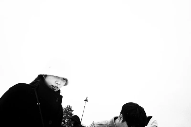 Thierry · 07/01/2026 · 3840 x 2560 Cette photographie en noir et blanc montre deux personnes, dont une semble être un enfant, en position penchée, probablement pour observer ou ramasser quelque chose. Le sujet principal est flou, suggérant un mouvement ou une attention focalisée sur un détail au sol.La composition est simple, avec un cadrage serré qui isole les personnages. La lumière est douce et diffuse, créant des contrastes atténués. L’ambiance est intimiste et presque mystérieuse, renforcée par le flou et le monochrome. Le style évoque une touche documentaire ou artistique, capturant un moment spontané et poétique.
