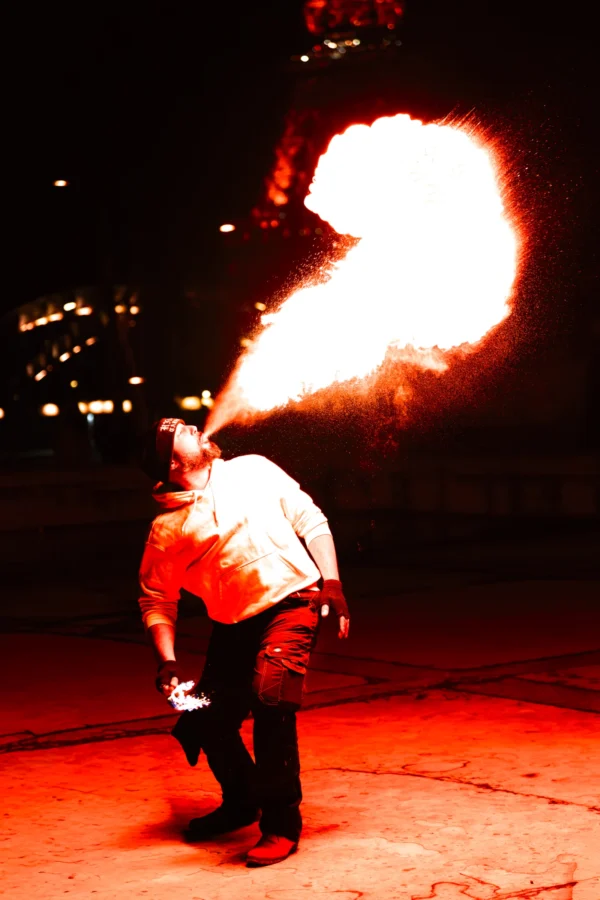 Thierry · 24/01/2026 · 2560 x 3840 Cette photographie met en scène un **artiste cracheur de feu** comme sujet principal. Le cadrage est serré, centré sur lui, avec une composition dynamique.La lumière est dramatique, avec des éclats de feu orange-jaune très vifs, contrastant avec l'obscurité ambiante. Les couleurs dominantes sont les teintes chaudes du feu et les tons sombres de la nuit.Le style est **artistique et spectaculaire**, évoquant une ambiance **théâtrale et intense**, presque mystique, typique des performances de feu en extérieur nocturne.