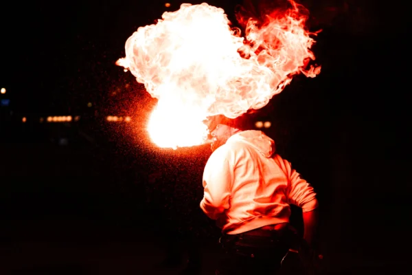 Thierry · 24/01/2026 · 3840 x 2560 Cette photographie met en scène un **artiste manipulant des flammes**, sujet principal captivant au centre. La **composition** est dynamique, avec un cadrage serré sur la silhouette et l'explosion de feu en arrière-plan.La **lumière** est dramatique, contrastée, avec des éclats vifs et des ombres profondes. Les **couleurs dominantes** sont les tons chauds (orange, jaune) des flammes, sur un fond noir, créant un **style** visuel saisissant et presque cinématographique.L’**ambiance** est intense, mystique et spectaculaire, évoquant la maîtrise du feu et une énergie envoûtante.