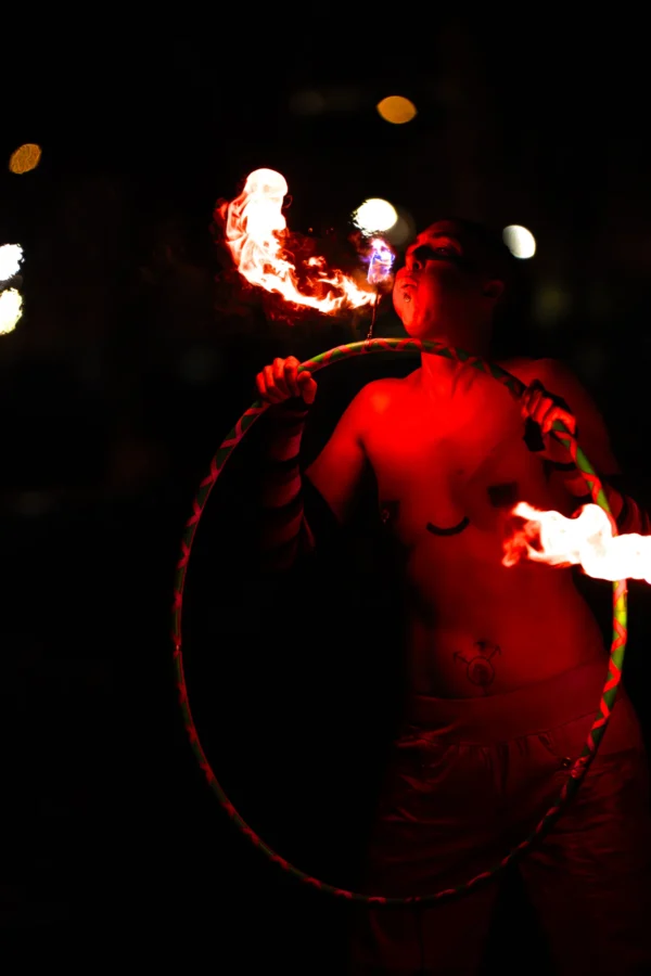 Thierry · 24/01/2026 · 2560 x 3840 Cette photographie met en scène un artiste manipulant des torches enflammées, sujet principal captivant. La composition est dynamique, centrée sur le mouvement des flammes et le corps partiellement visible. Le cadrage serré isole le sujet dans un cercle lumineux rouge, créant un effet dramatique.Les couleurs dominantes sont le rouge vif des flammes et des cercles lumineux, contrastant avec le noir de l’arrière-plan. La lumière est intense et contrastée, soulignant l’action. Le style est artistique et théâtral, évoquant une ambiance mystique et énergique, typique des spectacles de feu.