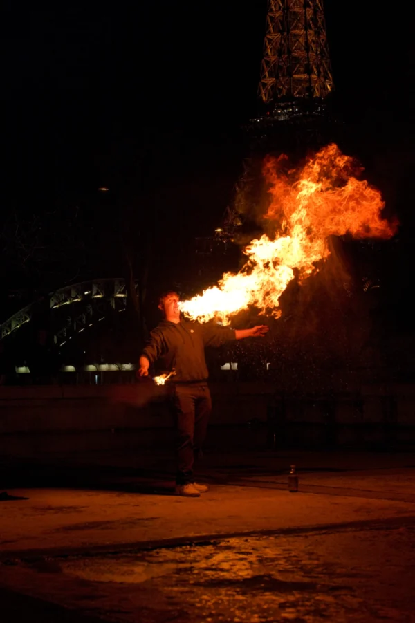 Ahmet · 24/01/2026 · 1706 x 2560 Cette photographie capture un artiste manipulant une boule de feu enflammée. Le sujet principal est le performeur, dont le visage est flouté, concentré sur son geste.La composition est dynamique, avec un cadrage serré sur l'action. L'arrière-plan sombre et flou met en valeur la lumière intense des flammes. Les couleurs dominantes sont les teintes chaudes des flammes (oranges, jaunes) contrastant avec l'obscurité ambiante.Le style est artistique et spectaculaire, évoquant une ambiance mystérieuse et intense, typique des spectacles de feu nocturne.