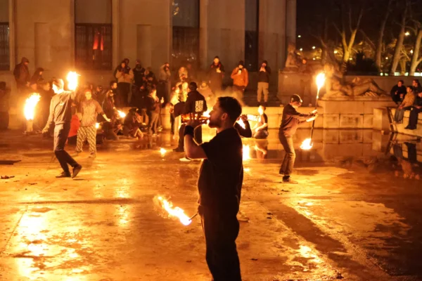 Laurence · 3472 x 2315 Cette photographie capture une scène de protestation nocturne. Le sujet principal semble être un groupe de manifestants en mouvement, certains brandissant des torches.La composition montre une rue étroite avec des personnes en action, encadrées par des bâtiments. Le cadrage est serré, mettant en valeur les visages et les gestes intenses.Les torches créent une lumière vive et contrastée, dominant les couleurs chaudes (oranges, jaunes). L’ambiance est tendue et dynamique, évoquant l’énergie et la révolte. Le style est documentaire et spontané, reflétant une scène authentique et chargée émotionnellement.
